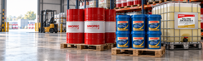 Industrial warehouse scene showing large red and blue SNOPEC branded barrels and a white IBC tote on pallets, with a forklift in the background.